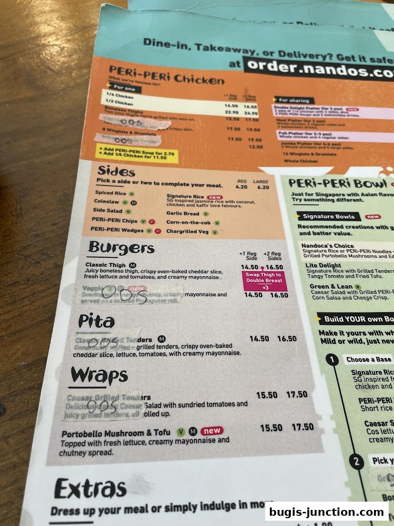 A close-up view of a Nando's menu featuring chicken dishes, burgers, pitas, and wraps.