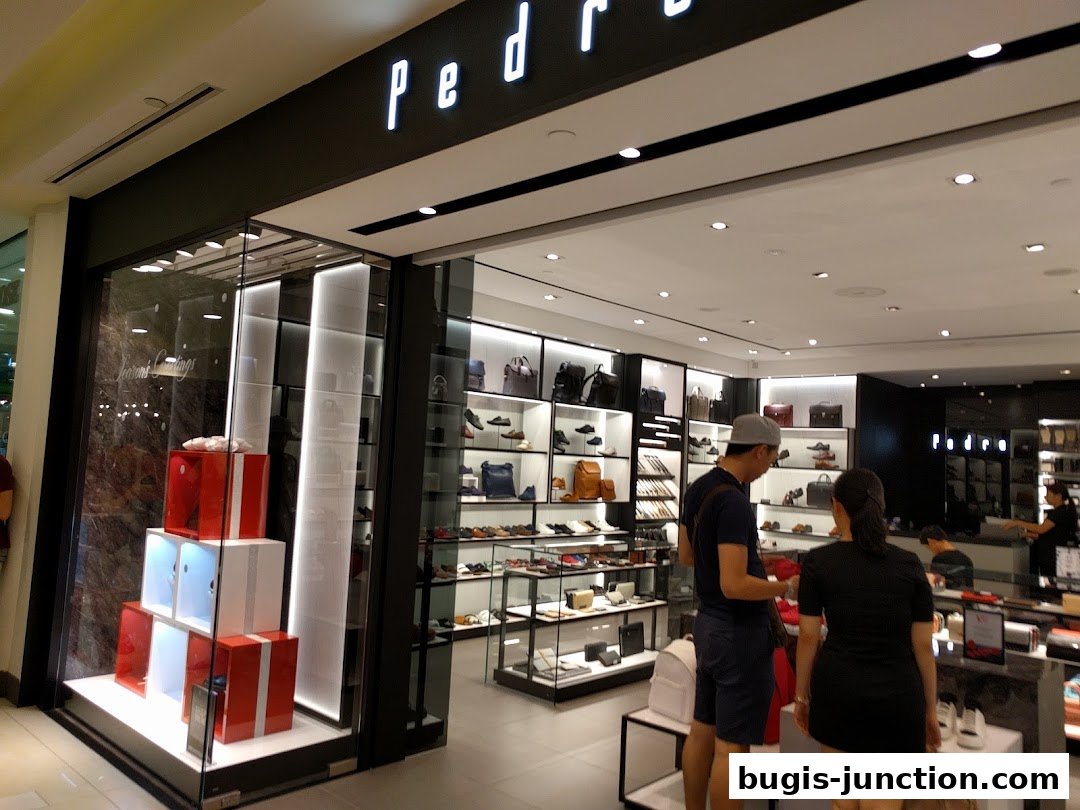 Interior view of a PEDRO store showcasing shoes and bags with customers browsing.