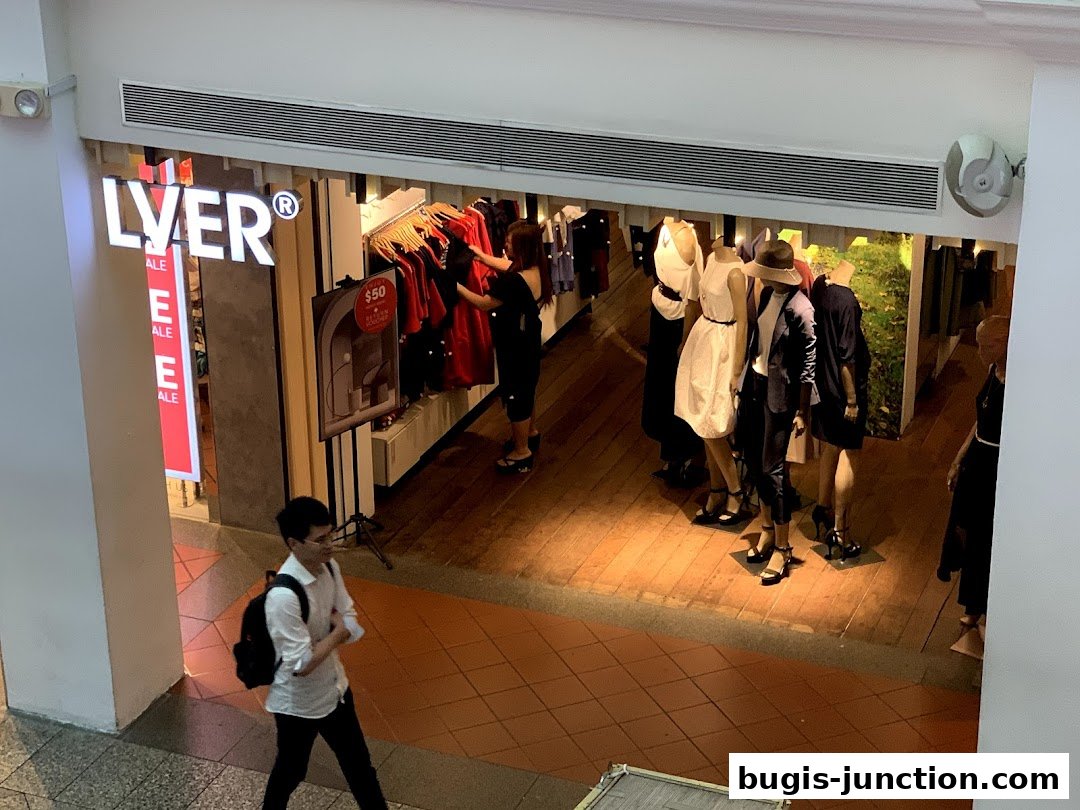 A fashion store interior with mannequins displaying outfits and clothing racks.