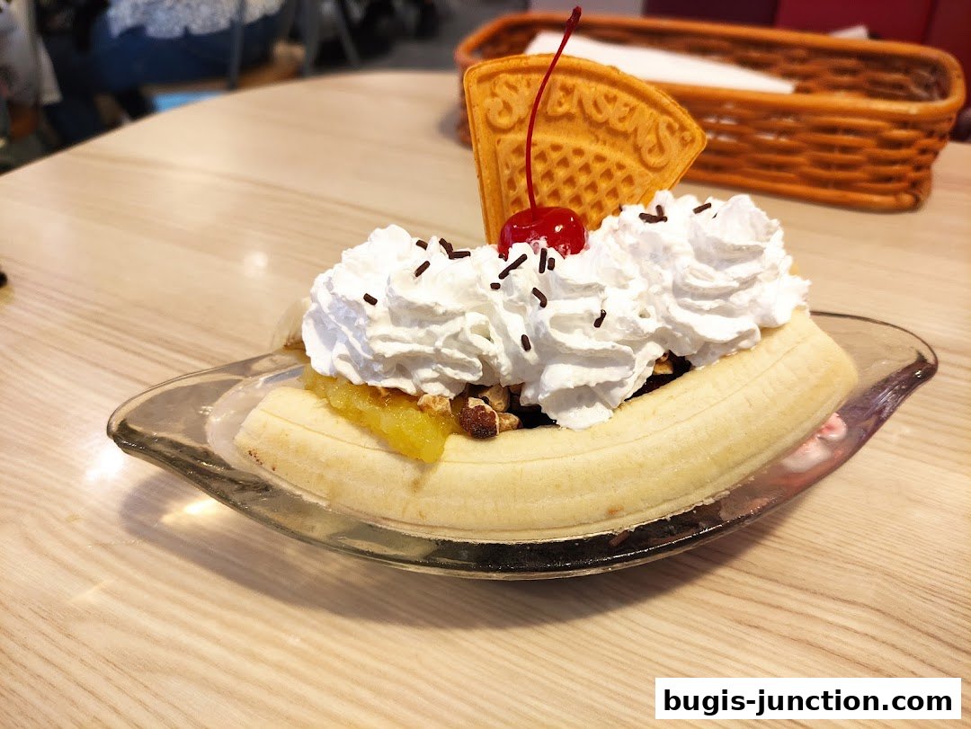 A delicious banana split dessert with whipped cream, cherry, and waffle.