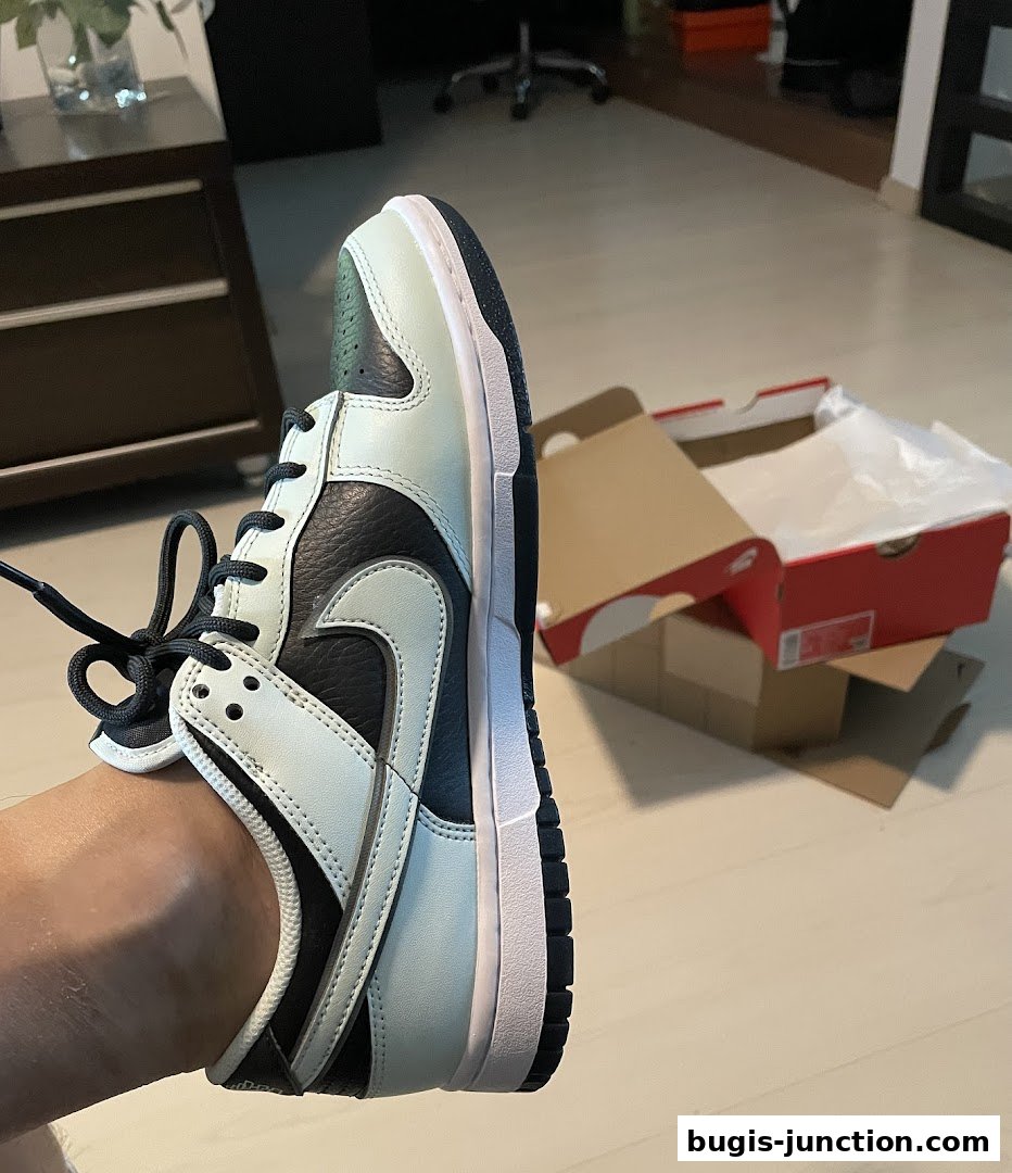 A close-up of a person wearing a Nike sneaker with its box in the background.