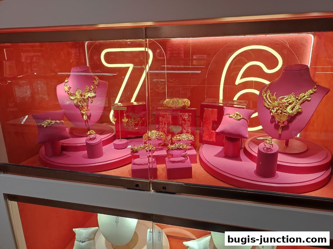 A display of exquisite gold jewelry, including necklaces, bracelets, and rings, showcased on pink stands against a red background.