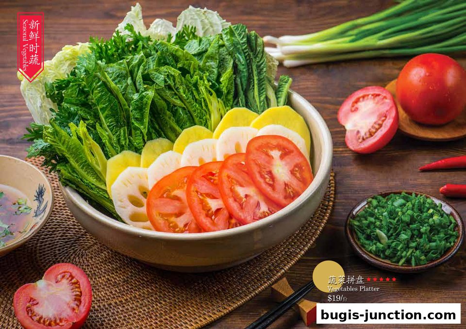 A vibrant platter of fresh vegetables, including lettuce, tomatoes, lotus root, and potatoes, ready for hotpot.