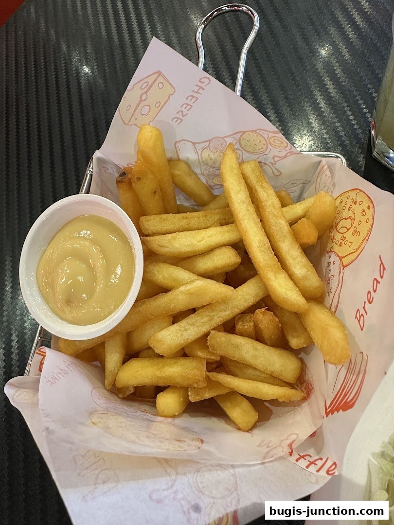 A basket of golden french fries served with a side of dipping sauce.