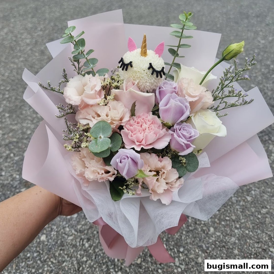 A hand holds a pastel-colored flower bouquet featuring a whimsical unicorn decoration.