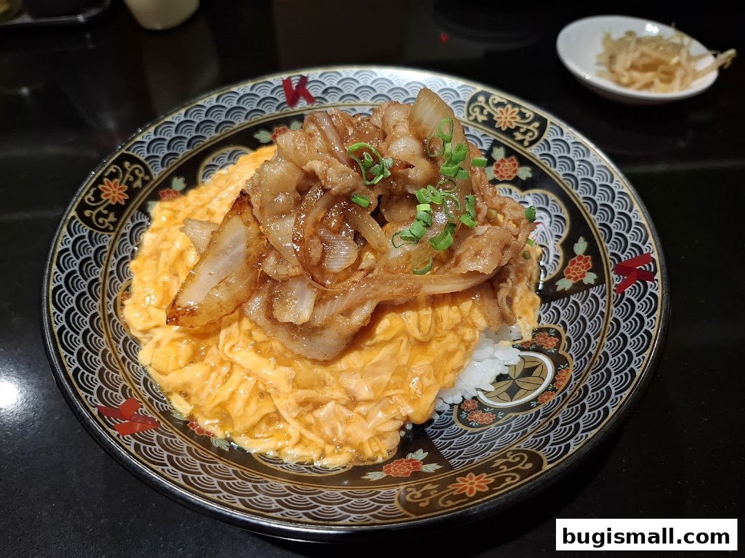 A close-up of a delicious scrambled egg rice bowl topped with savory pork and onions.