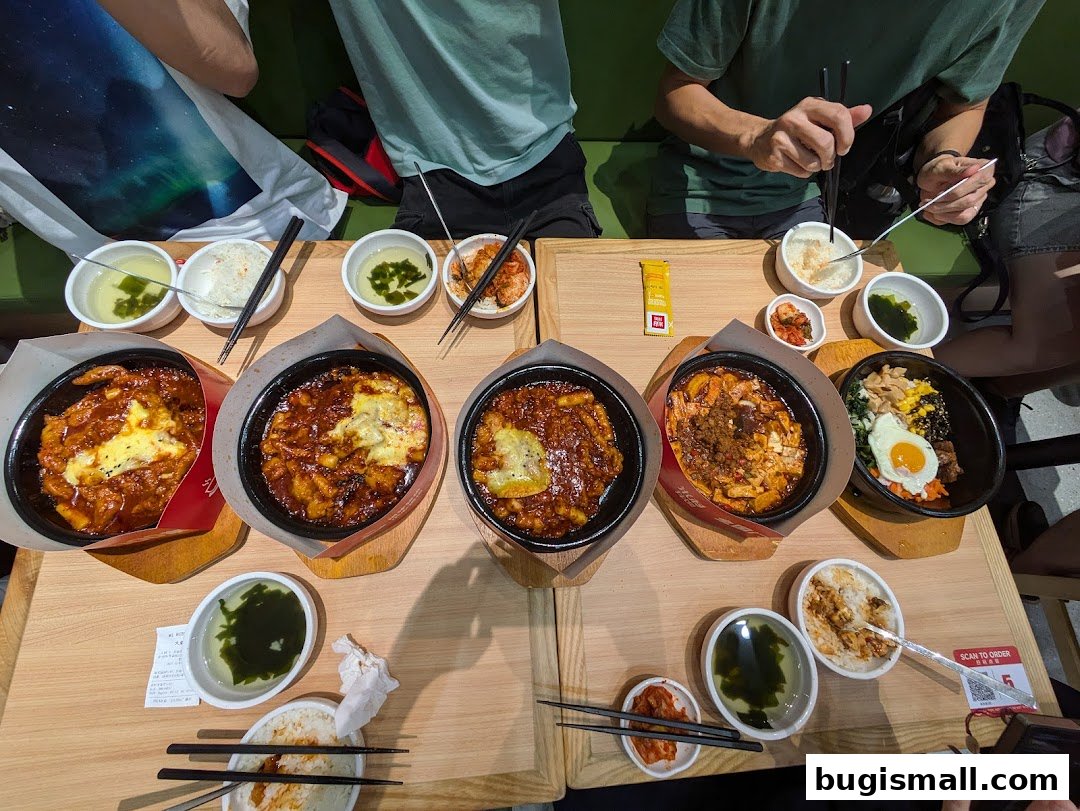 A table filled with Korean dishes including bibimbap, tteokbokki, and side dishes.