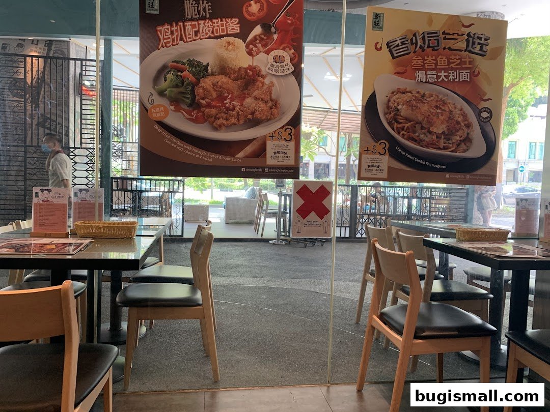 Interior view of Xin Wang Hong Kong Café with promotional posters and dining tables.
