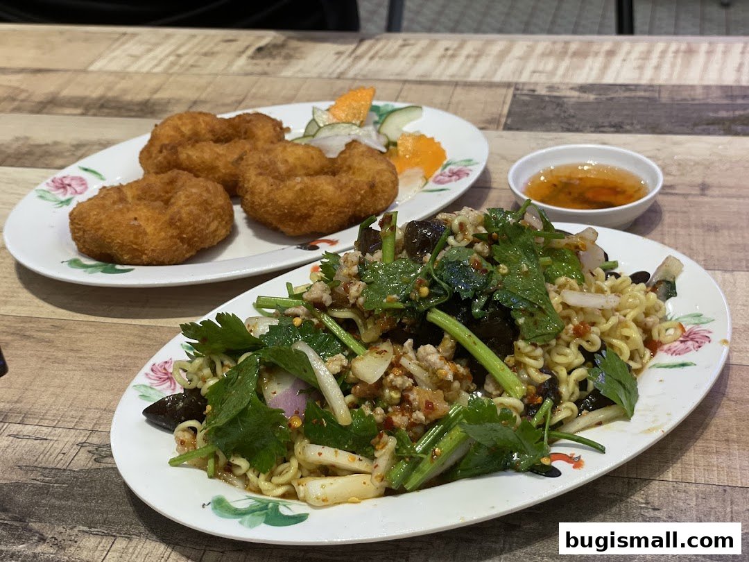 Two plates of Thai food, one with fried shrimp cakes and the other with a noodle salad.