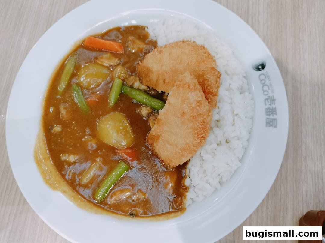 A plate of Japanese curry with rice and two pieces of fried chicken.