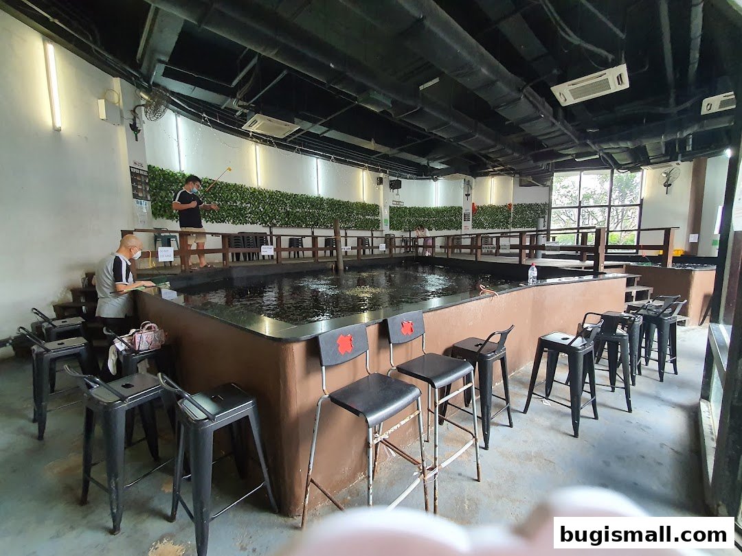 People fishing in an indoor pond with bar stools around the edge.