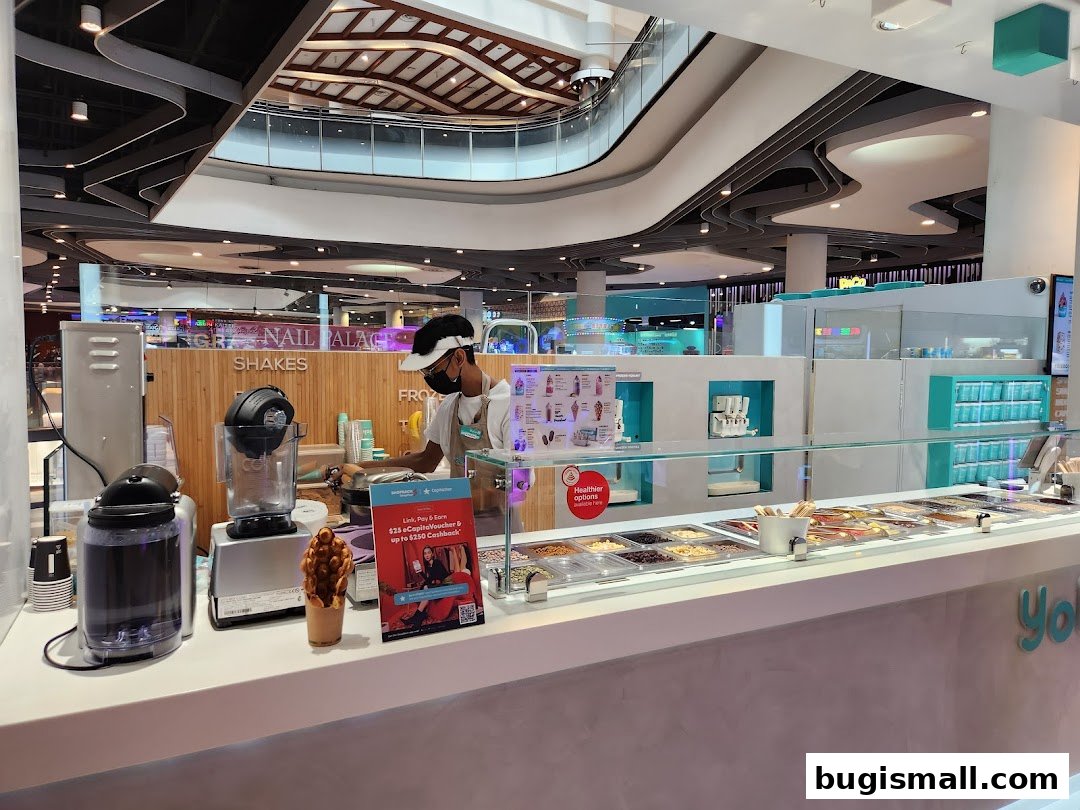 A Yolé frozen yogurt shop with a staff member serving customers and various toppings displayed.