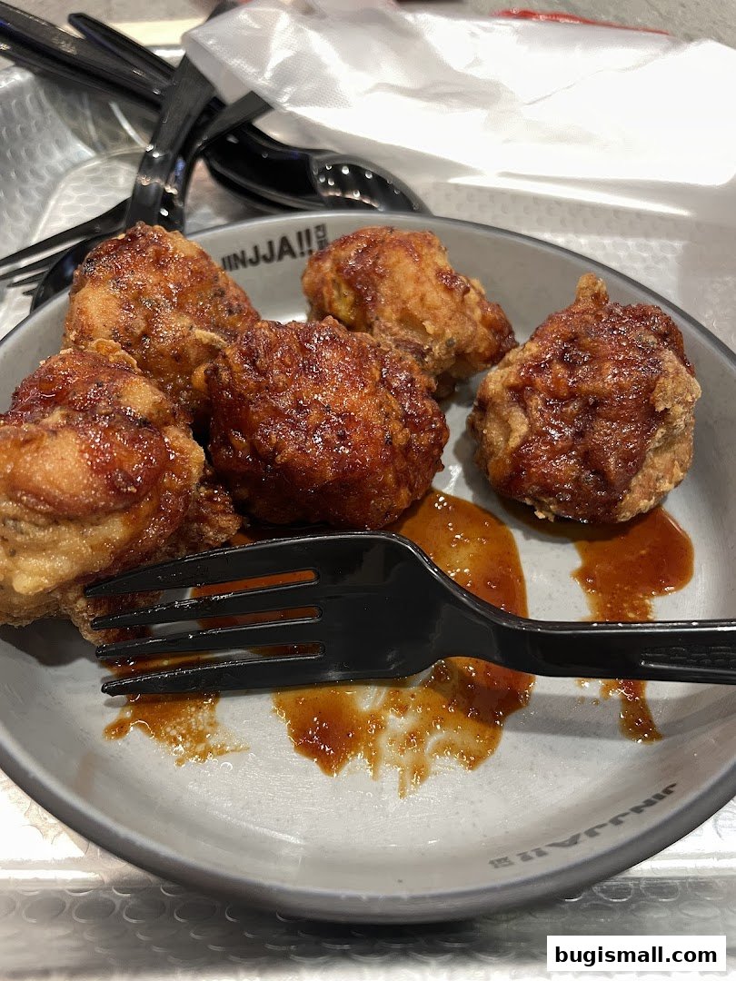 A plate of delicious Korean fried chicken with a glossy sauce and a fork.