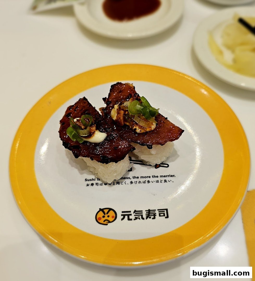Two pieces of sushi with grilled meat and green onions on a plate.