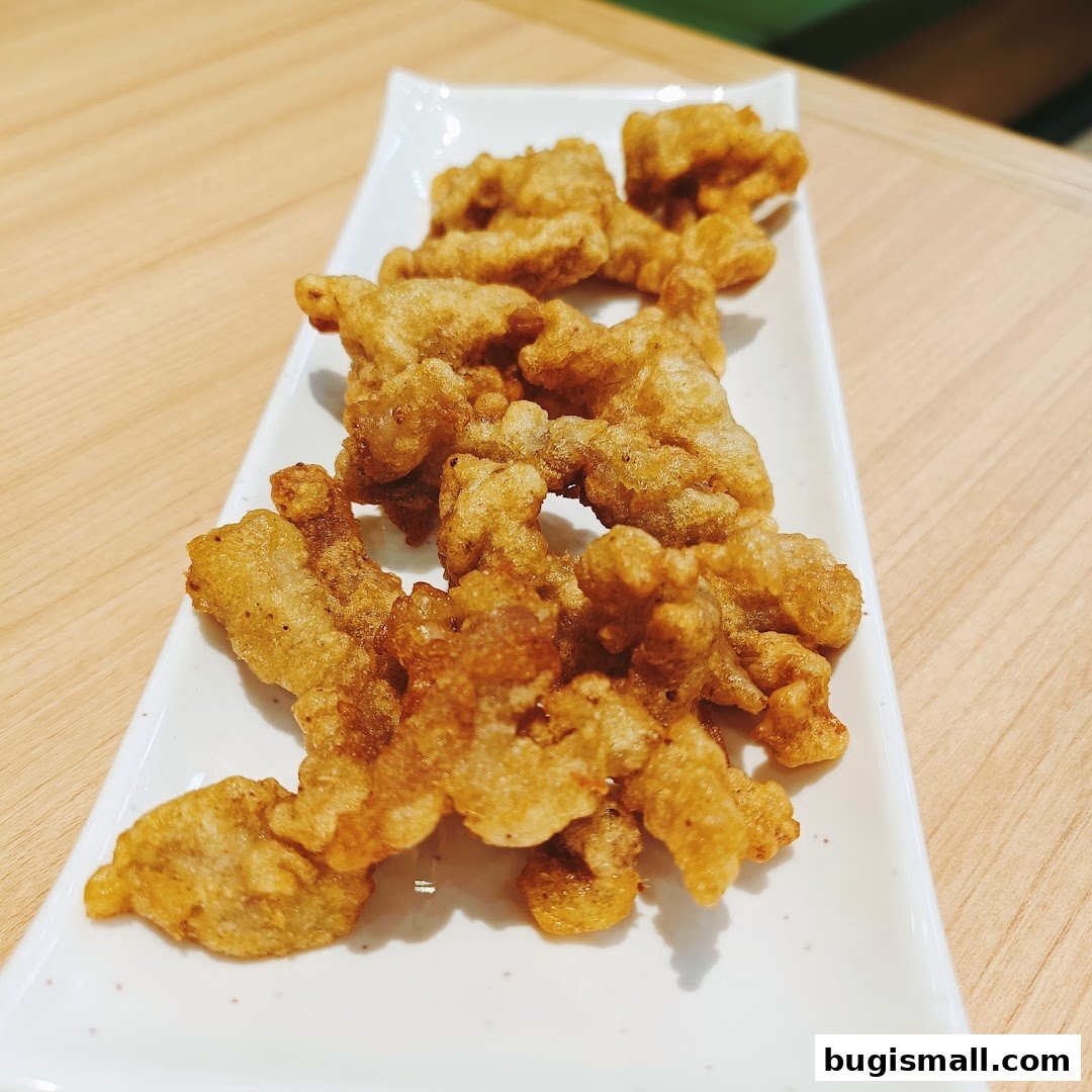 A white rectangular plate filled with golden-brown, crispy fried chicken pieces.