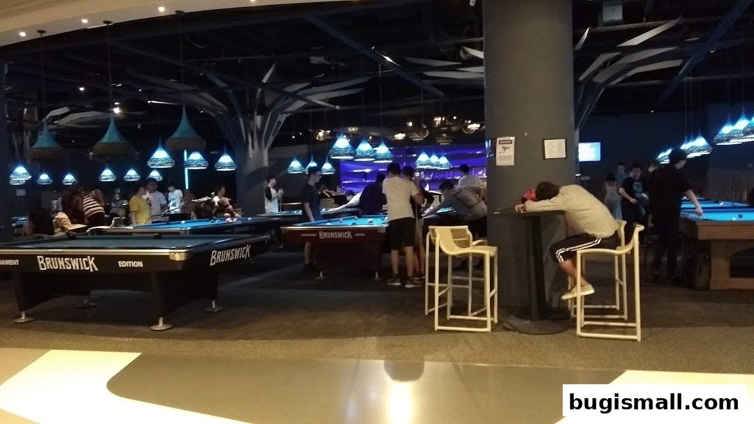 People playing pool in a dimly lit entertainment venue with stylish pendant lights.