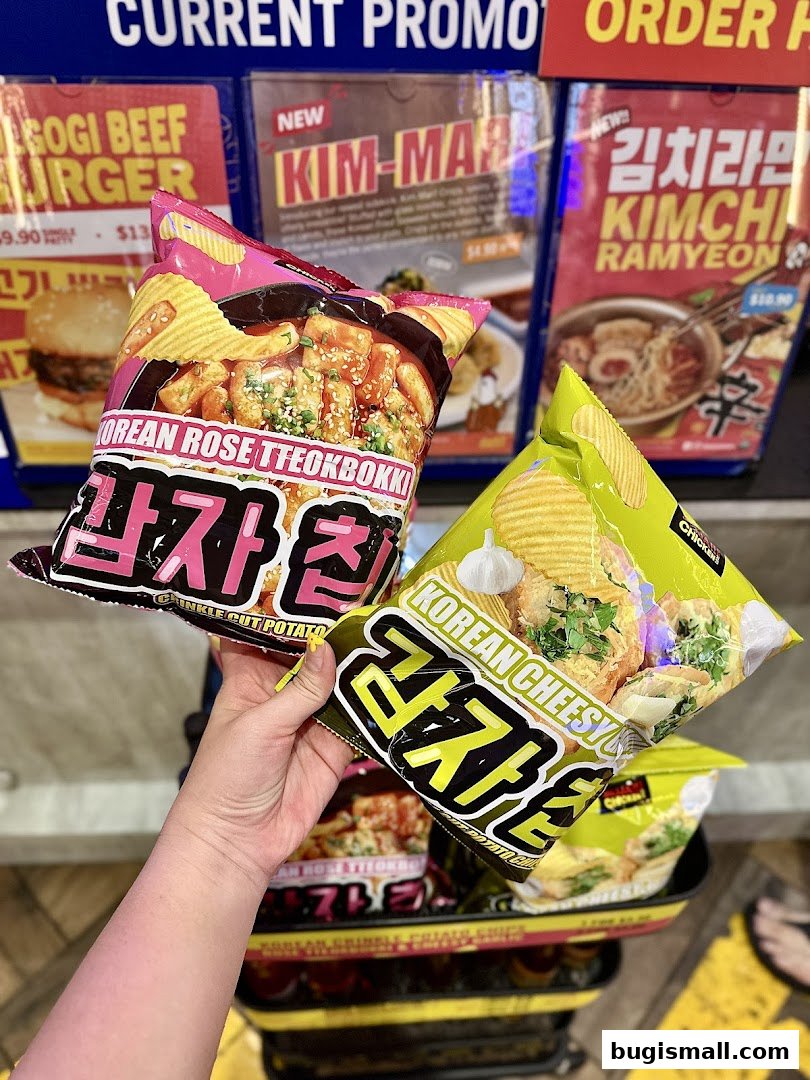 A hand holds bags of Korean-flavored potato chips in front of promotional posters.