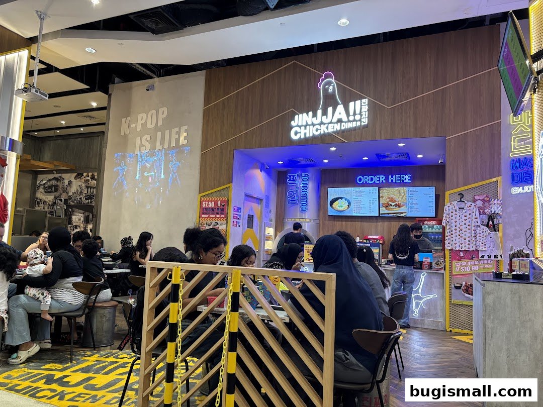 Diners are seated at tables inside JINJJA Chicken Diner, with the counter and menu visible.