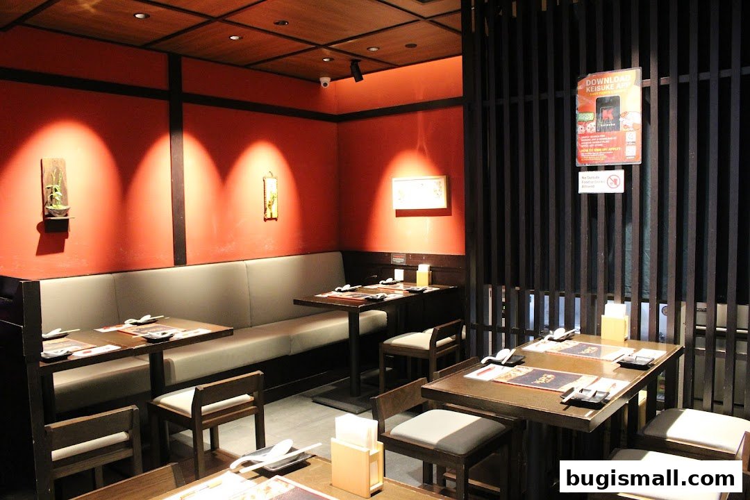 Interior of a restaurant with red walls, booth seating, and tables set for dining.