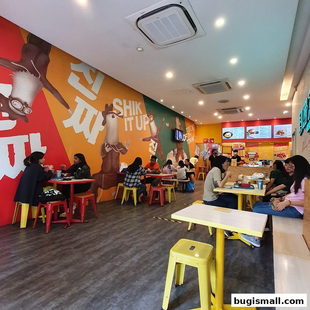 Interior of a JINJJA Chicken restaurant with customers dining and vibrant wall art.