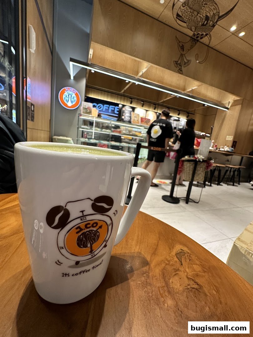 A close-up of a J.CO Donuts & Coffee mug with the shop interior in the background.