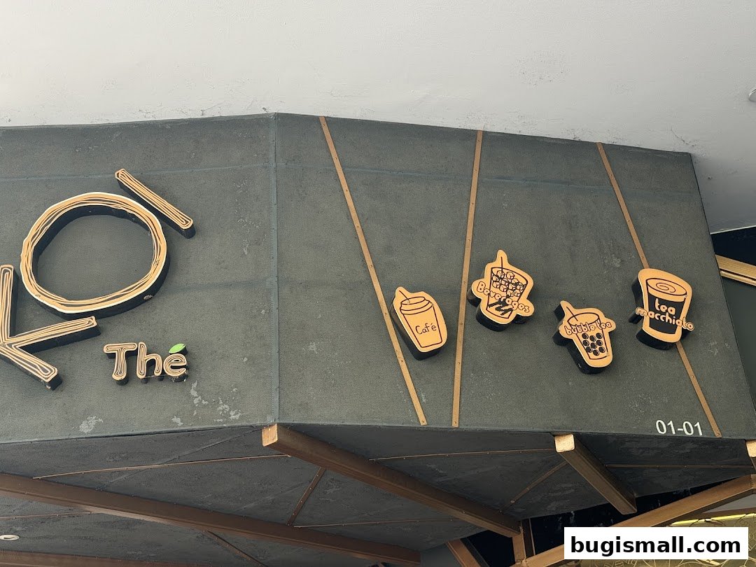 The KOI Thé Bugis shop sign with stylized beverage icons and the shop name.
