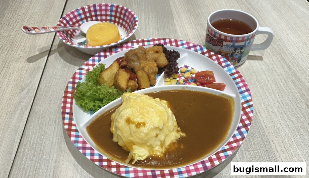 A delicious Japanese curry dish with omelet, fried chicken, and fries, served with a side of dessert and tea.