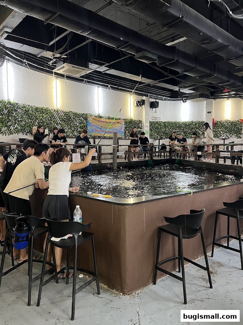People fishing at an indoor fishing pond with a competition banner.