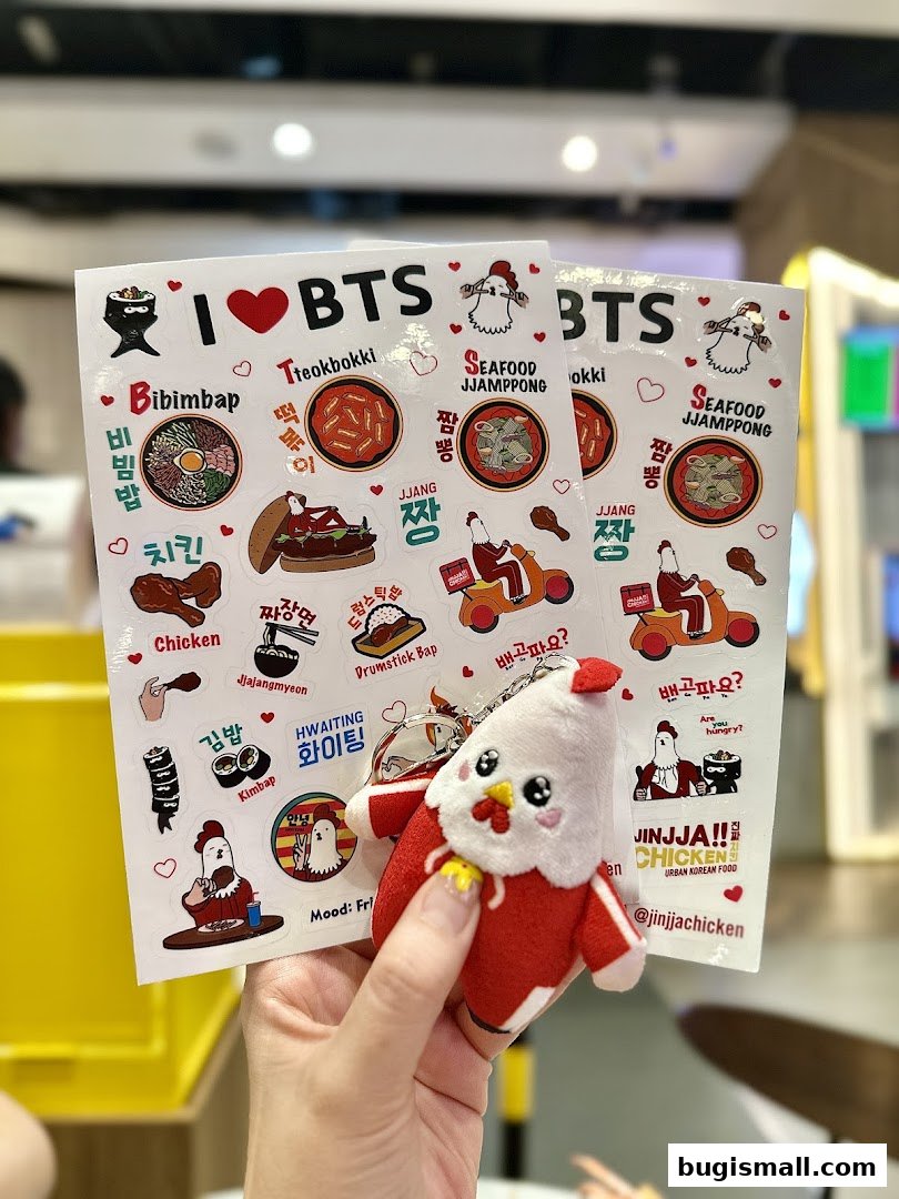 A hand holds stickers and a plush toy featuring Korean food and BTS.