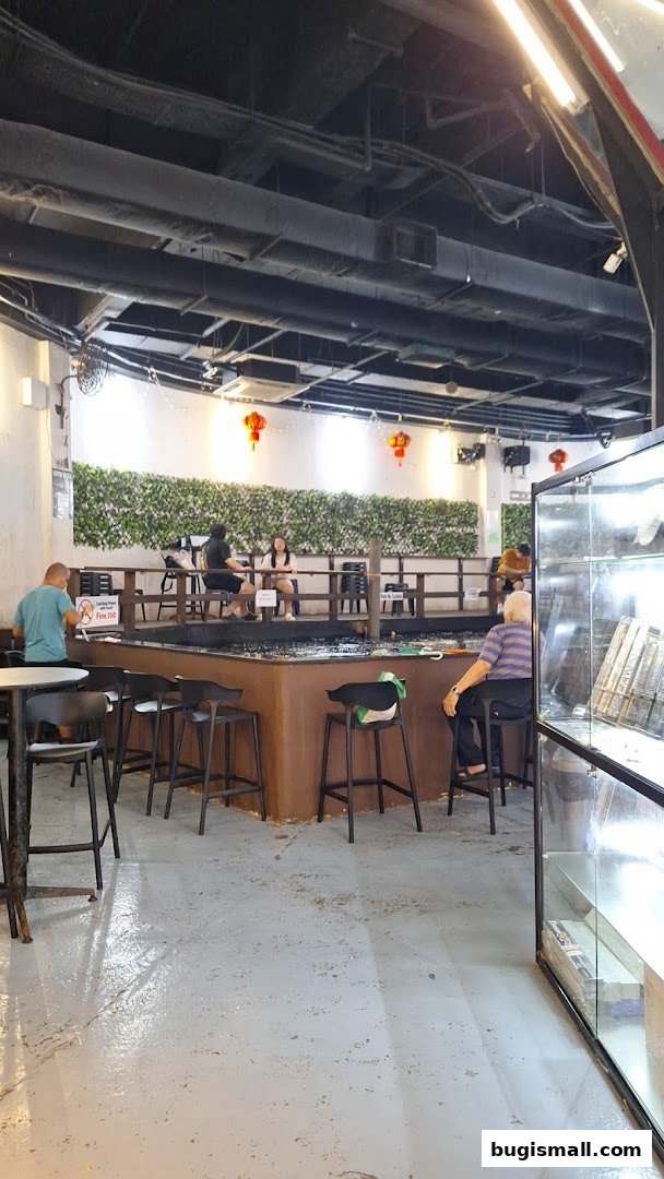 People are sitting around a large pond in a casual indoor setting with decorative lanterns.