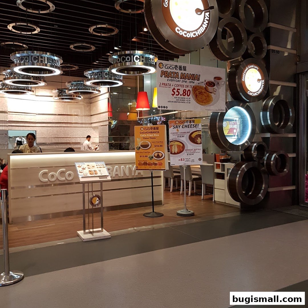 The entrance of CoCo Ichibanya restaurant with illuminated signage and promotional posters.