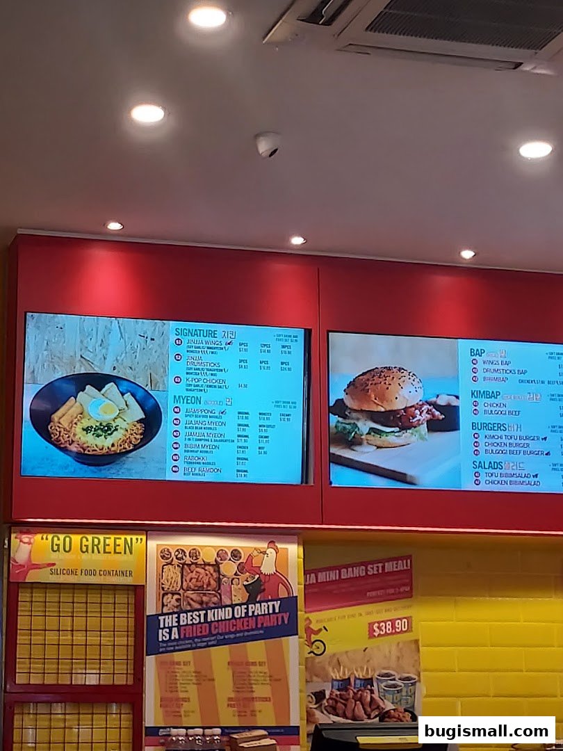 Digital menu boards displaying Korean fried chicken and other dishes at JINJJA Chicken.