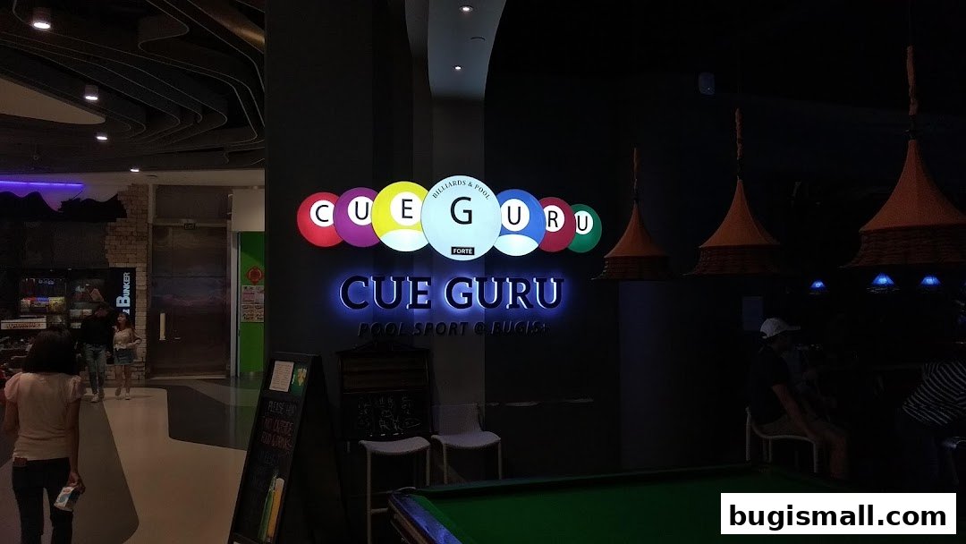 The illuminated sign for Cue Guru, a billiards and pool establishment, is displayed prominently.