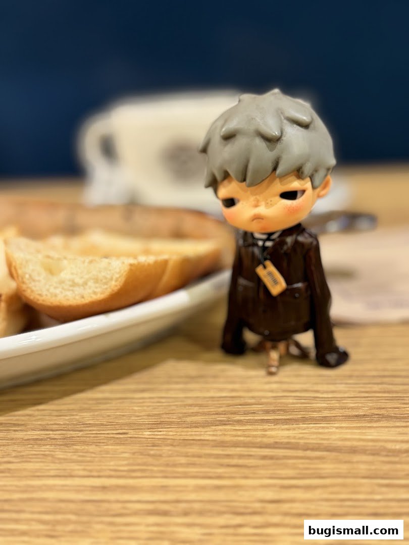 A small figurine sits on a wooden table next to a plate of bread slices.