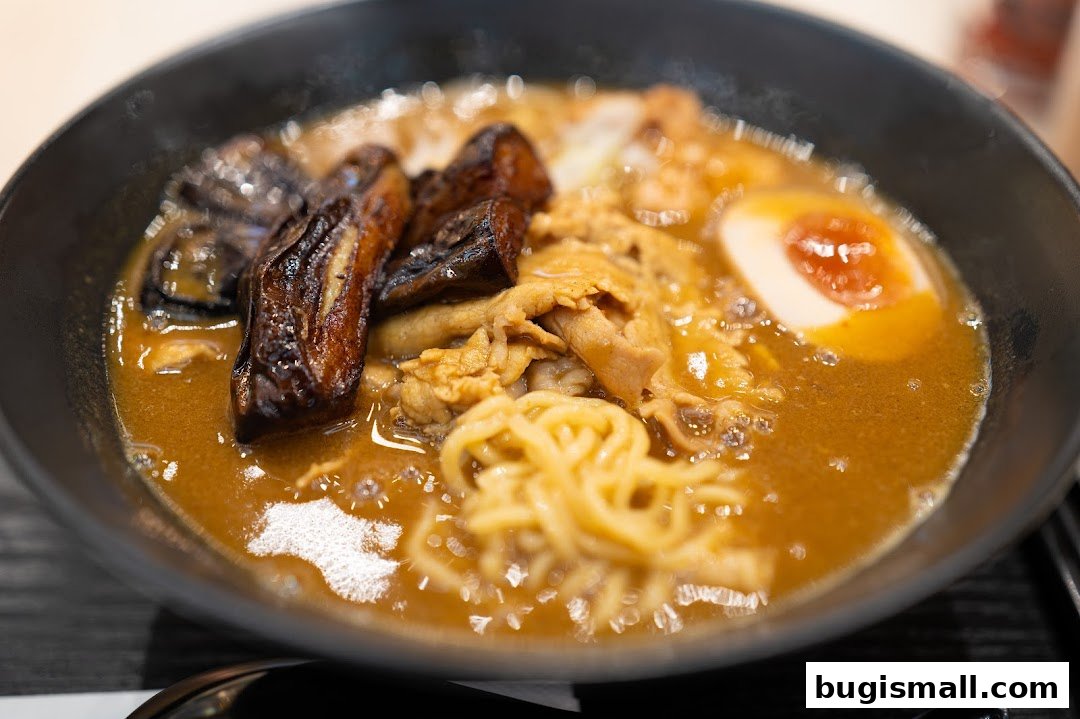 A close-up shot of a steaming bowl of Japanese curry ramen with tender meat and a soft-boiled egg.