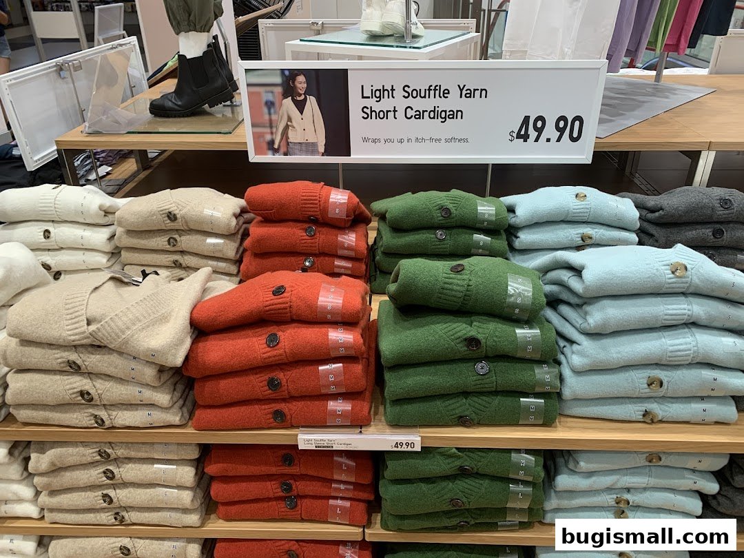Neatly folded stacks of colorful cardigans displayed on shelves in a retail store.