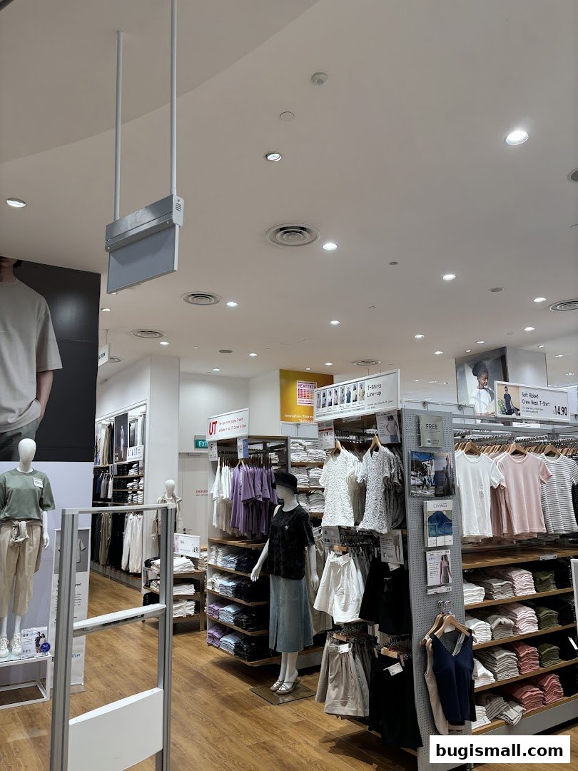 Interior view of a UNIQLO store showcasing folded and hung apparel, mannequins, and displays.