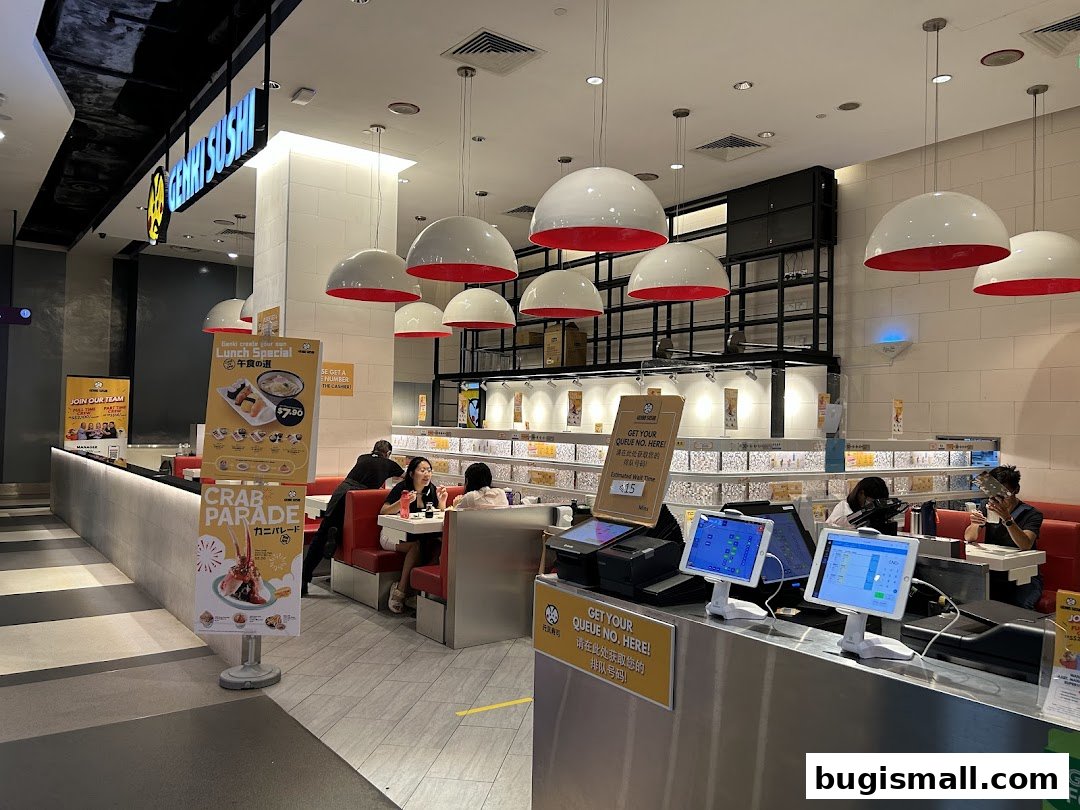 Interior of Genki Sushi Bugis with customers dining and ordering stations.