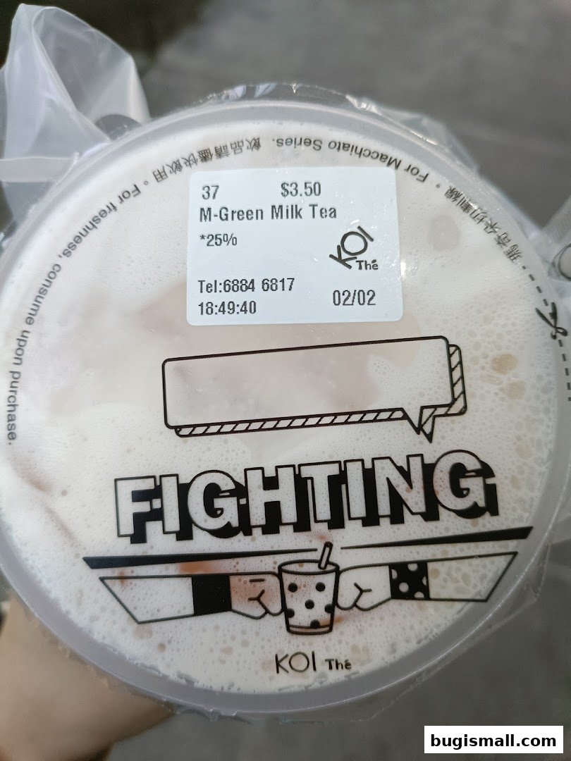 A cup of M-Green Milk Tea from KOI Thé with a 'FIGHTING' design on the lid.