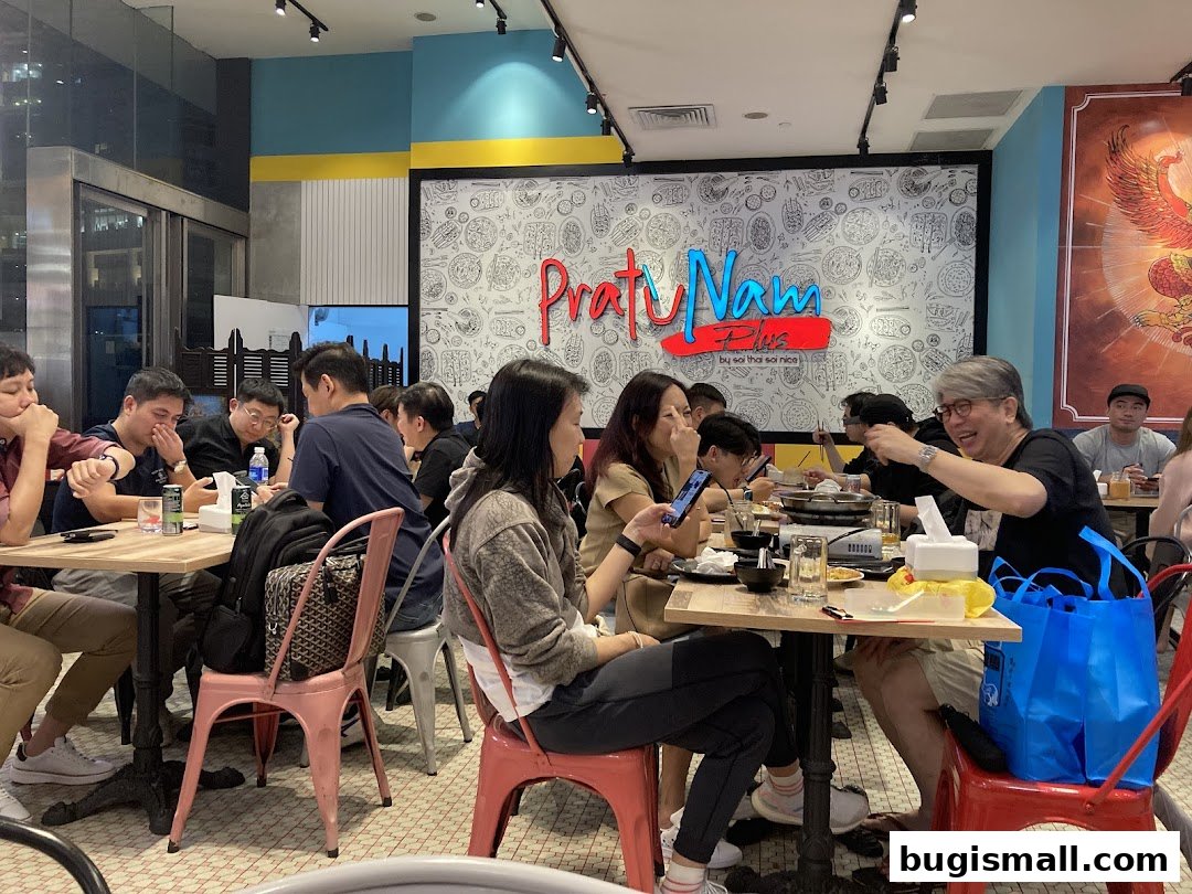 Diners enjoy a meal at Pratunam PLUS by Soi Thai Soi Nice, with a vibrant interior.