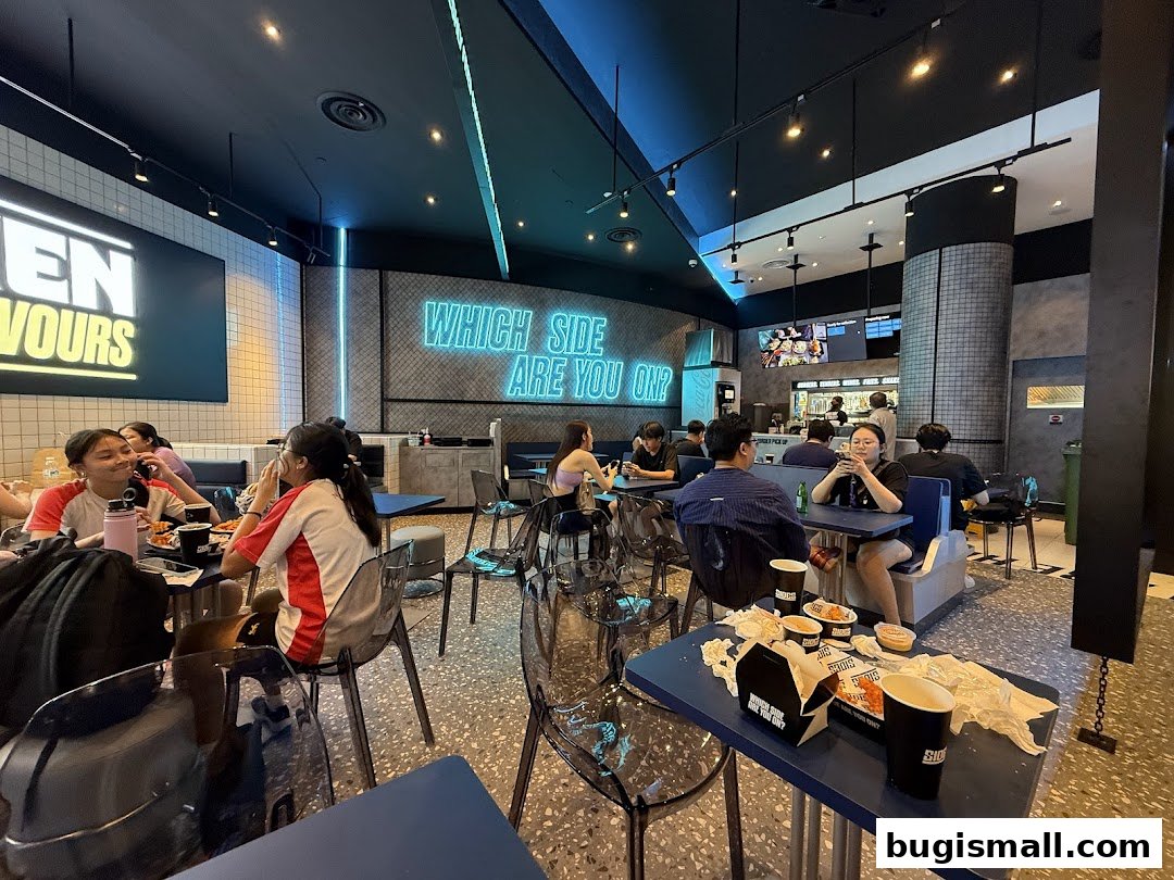Diners enjoying food and drinks inside a modern restaurant with neon signage.