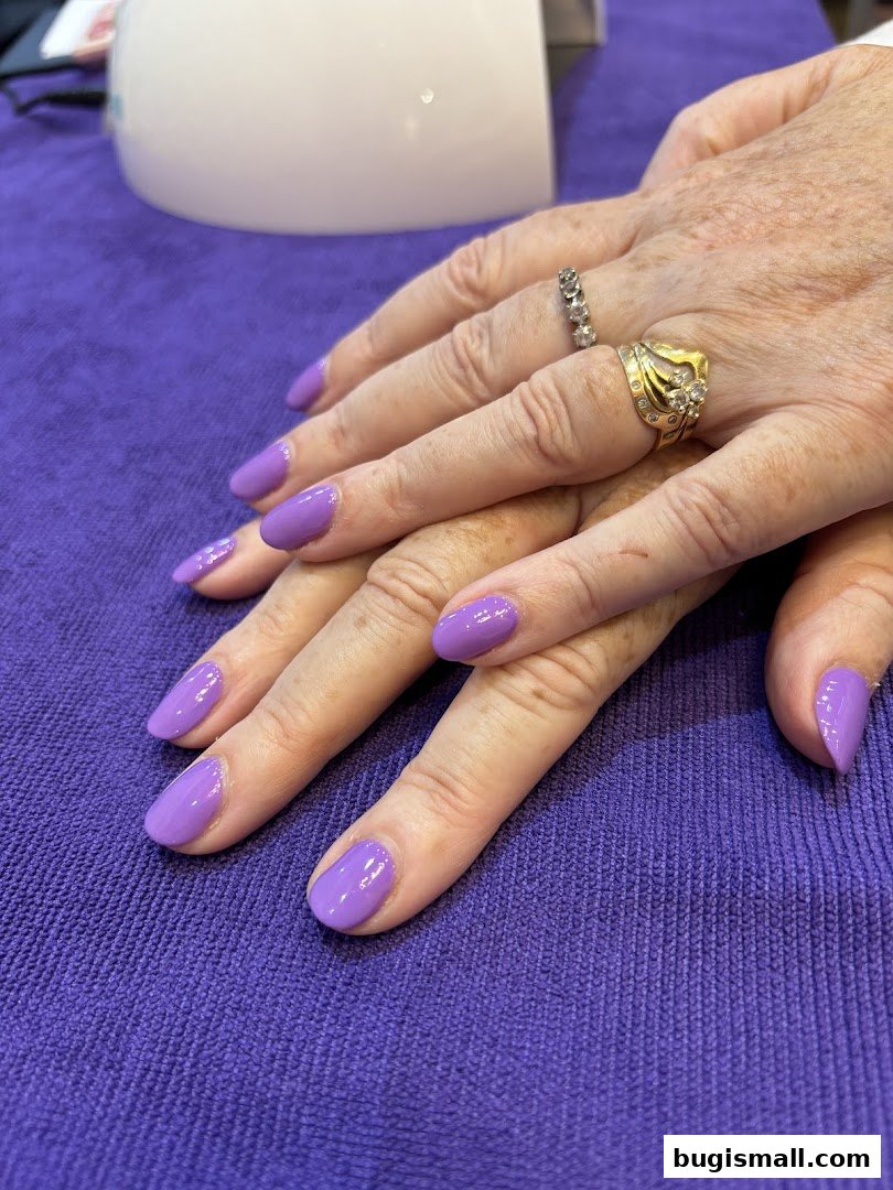 Close-up of hands with freshly painted lavender nails and rings.