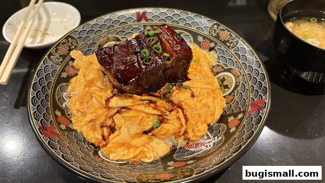 A delicious bowl of scrambled egg rice topped with braised pork belly and garnished with green onions.