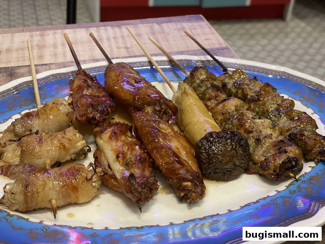 A plate of assorted grilled skewers, including chicken wings and mushroom.