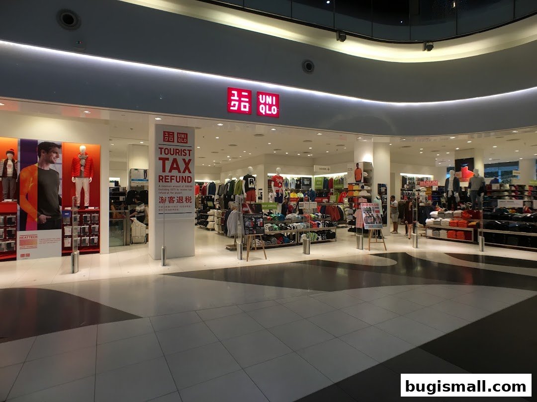 The entrance of a brightly lit Uniqlo store with mannequins and clothing displays.