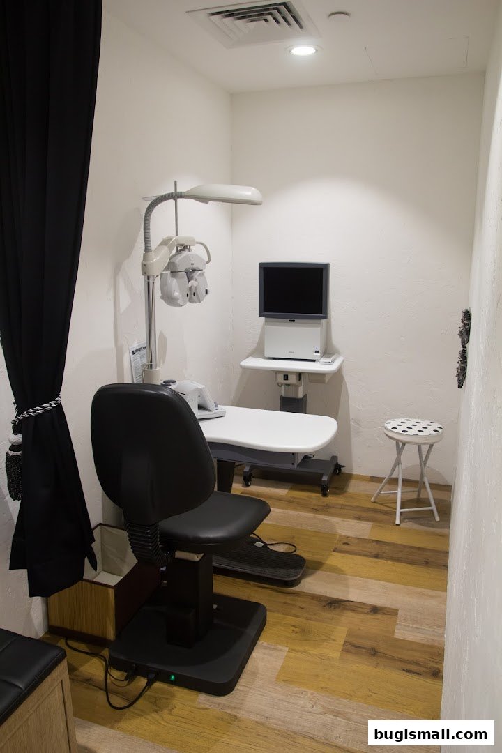 An eye examination room with a chair, phoropter, and diagnostic equipment.