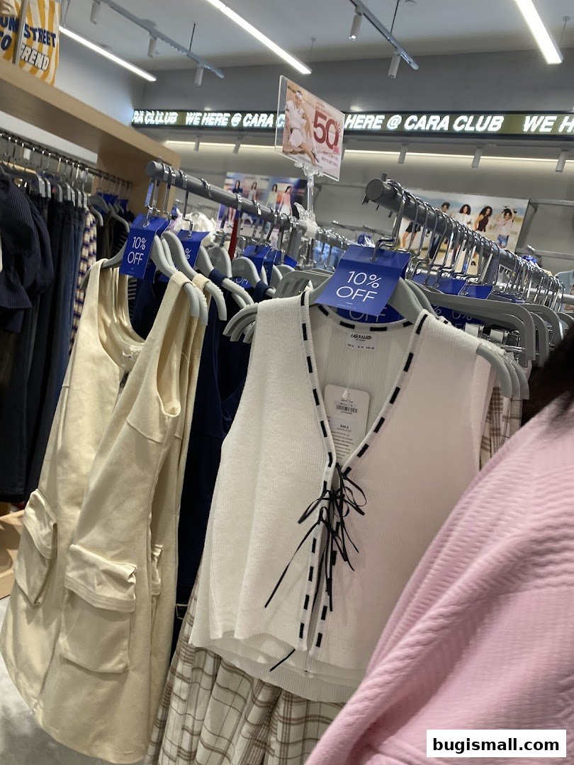 A clothing store interior with racks of trendy apparel and sale signs.
