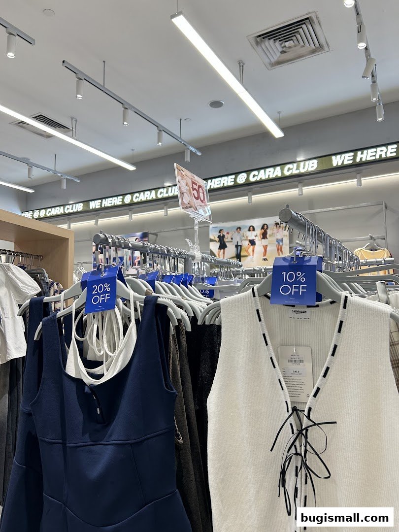 A clothing store interior with racks of clothes and sale signs.