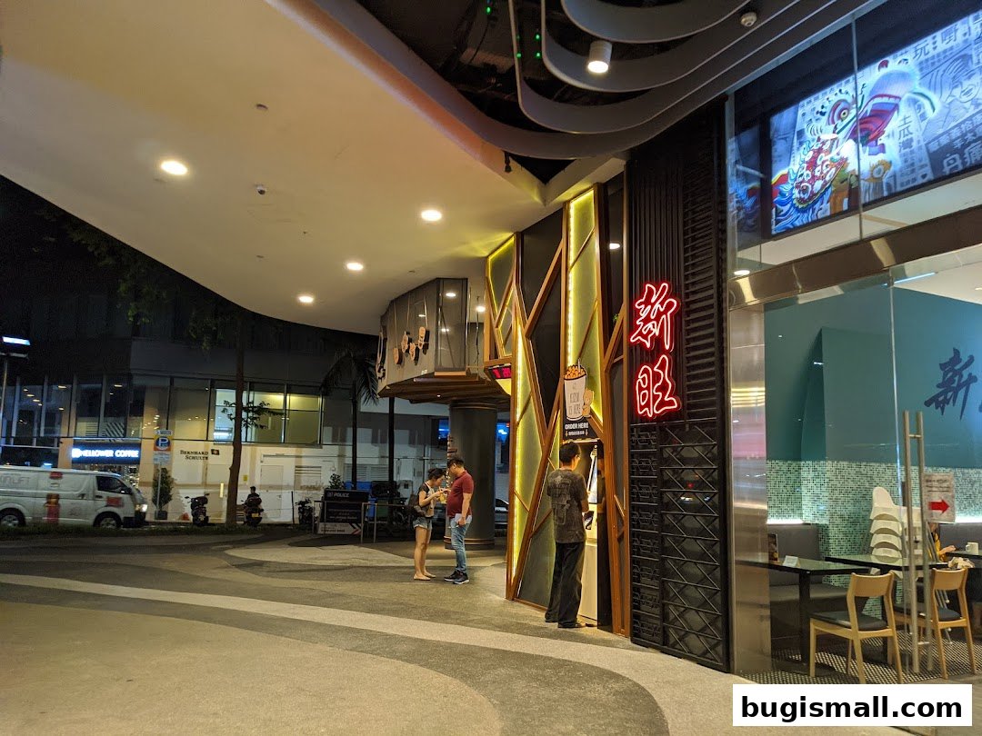 The exterior of KOI Thé Bugis with people standing outside and a neon sign.