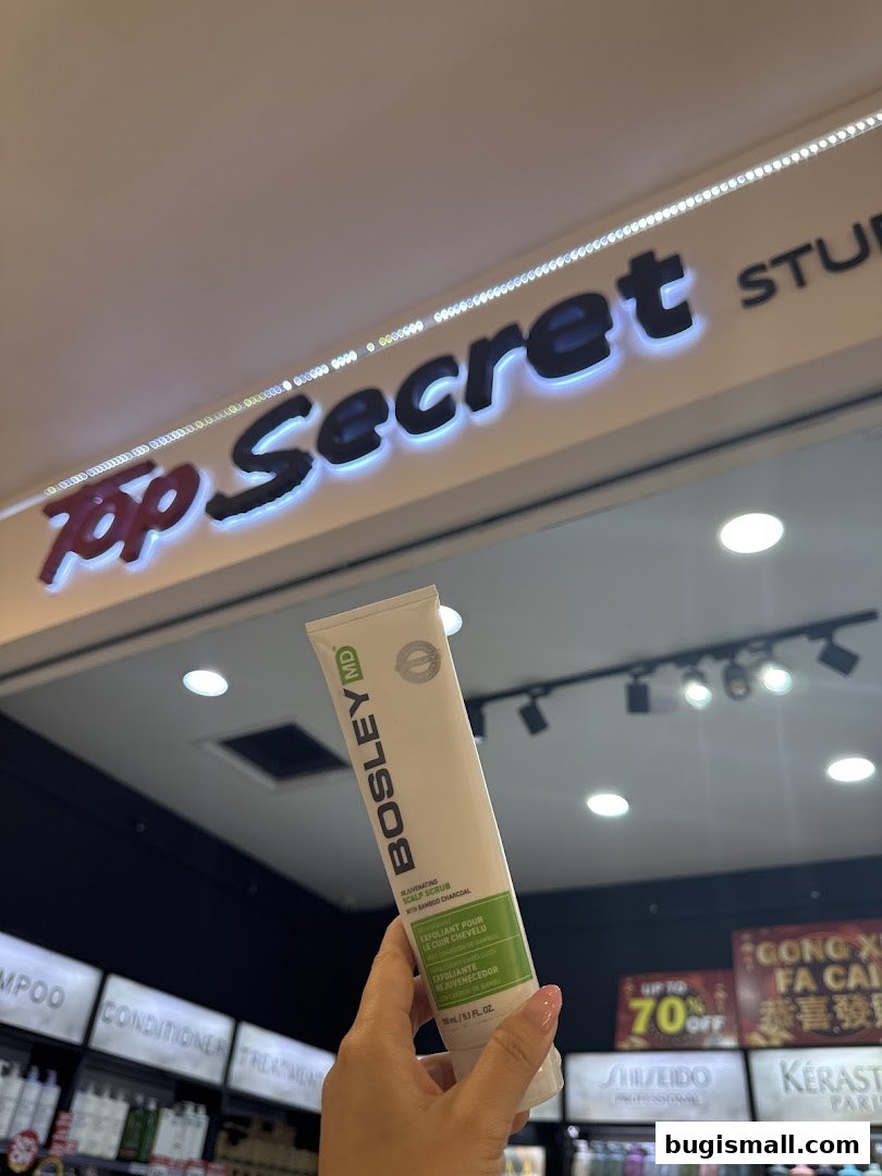 A hand holds a Bosley MD scalp scrub in front of a Top Secret Studio sign.